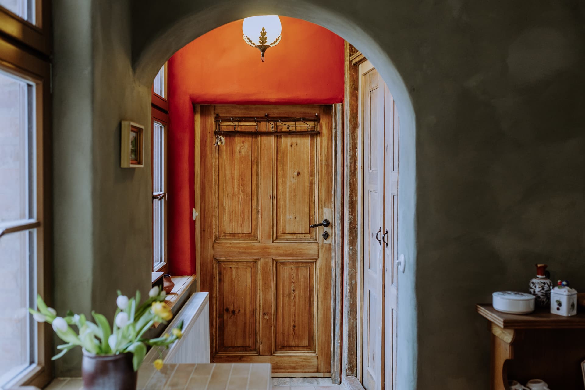 Sanft gerundeter Lehmputz-Durchgang mit Blick auf terrakottafarbene Wände und historische Zimmertüren