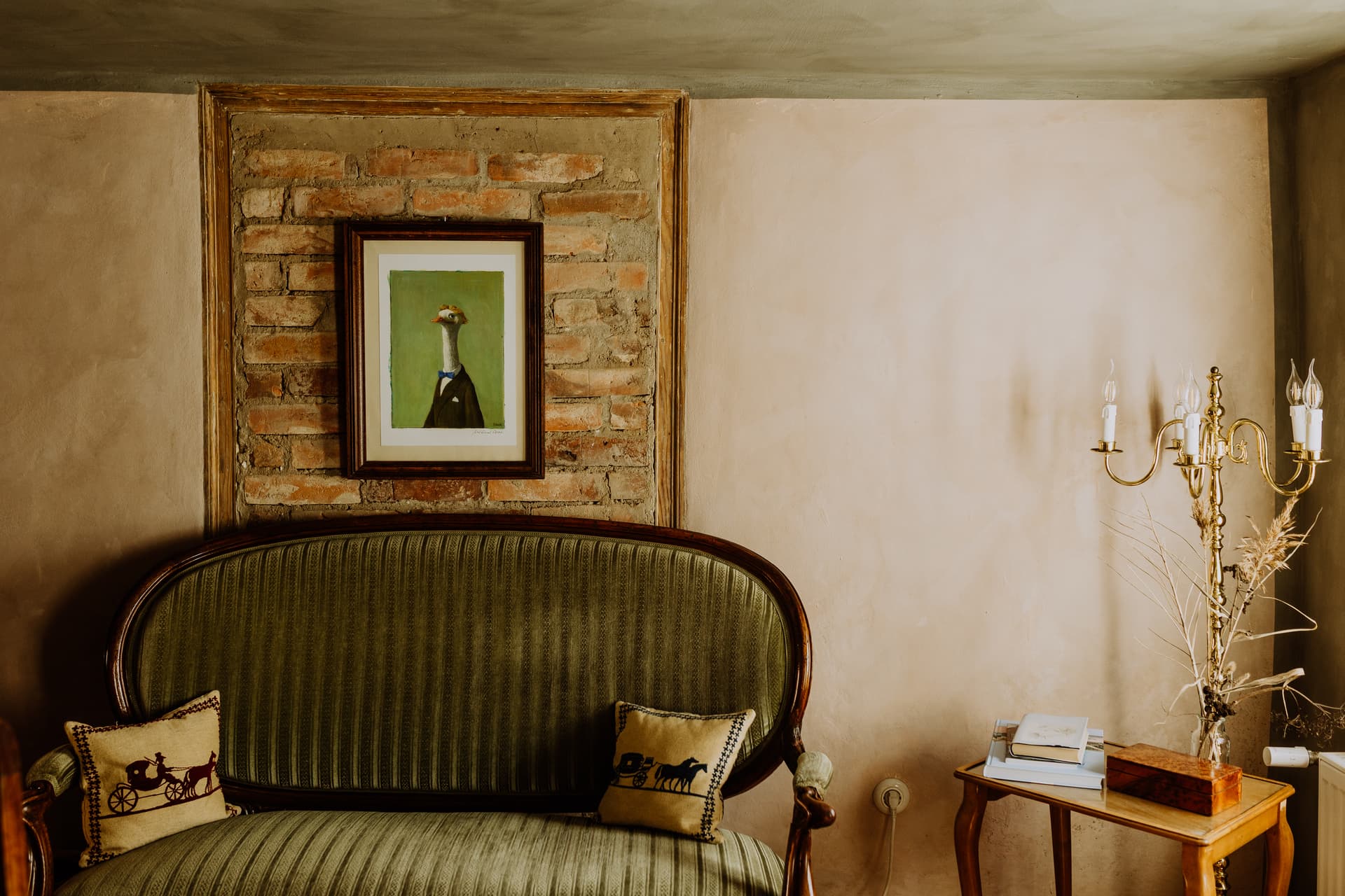 Biedermeier-Lounge mit grün gestreiftem Sofa, freigelegter Ziegelnische und Messing-Kandelaber