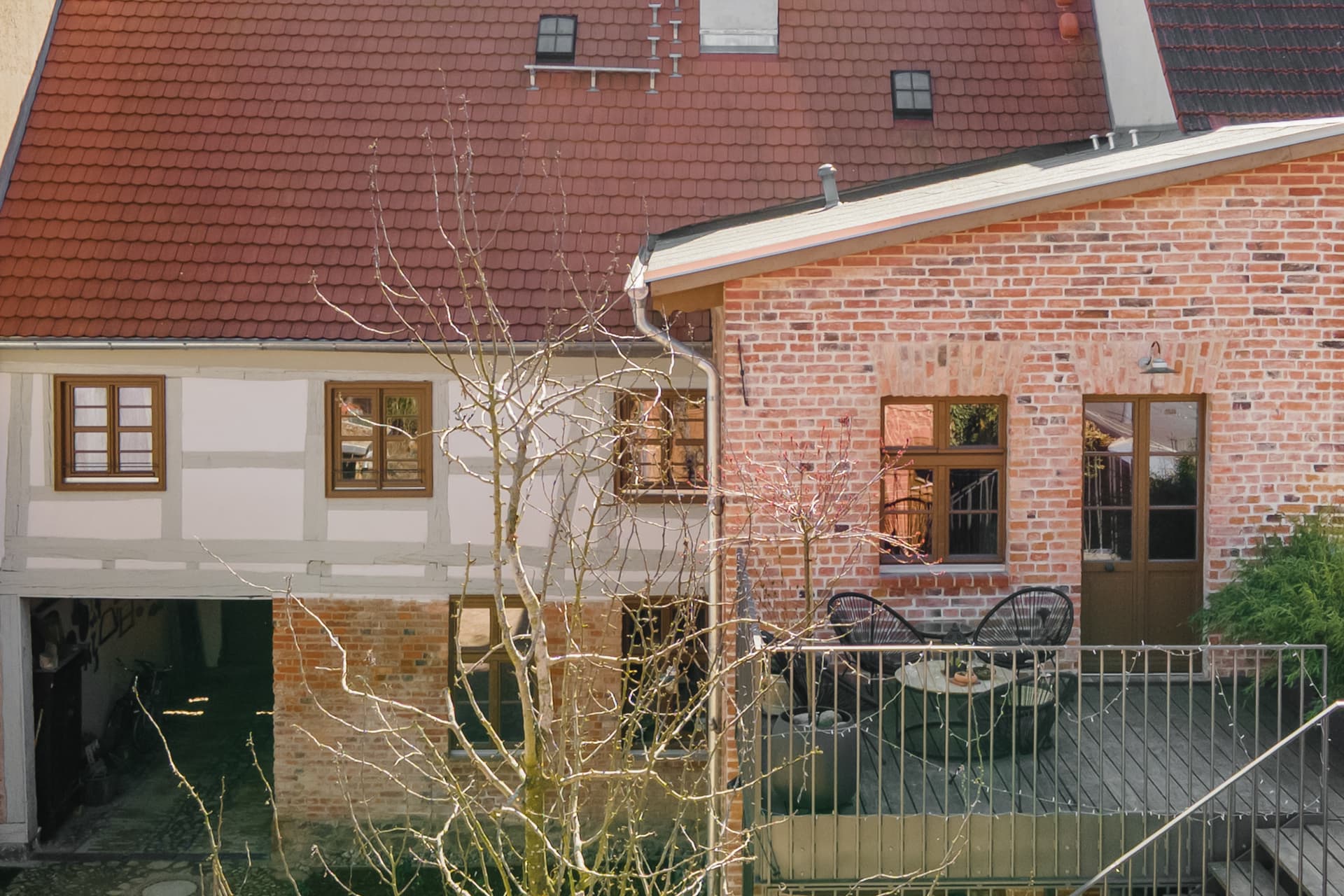 Innenhof und Fachwerkfassade der Alten Tischlerei Gransee mit weitläufiger Holzterrasse im Obergeschoss
